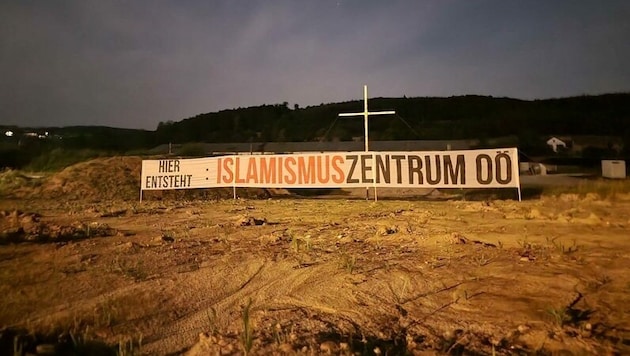 Dieses acht Meter hohe Holzkreuz und das rund 17 Meter lange Banner wurde 2021 auf einer Baustelle in Vöcklabruck angebracht. (Bild: zVg)