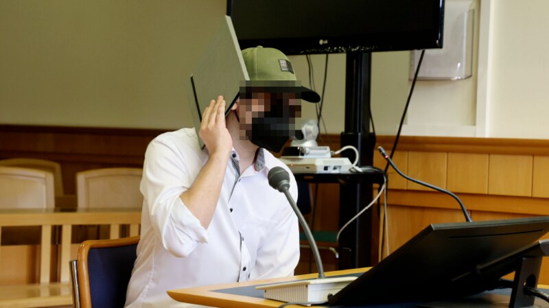 Wearing an FFP2 mask, sunglasses, a cap and a gray folder, the defendant appeared in the Vienna Regional Court. (Bild: Zwefo/Zwefo, Krone KREATIV)