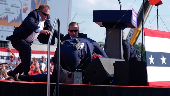 Immediately after the first shot, Secret Service men rush to Trump.