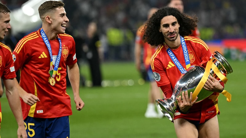 Marc Cucurella (rechts) drehte nach dem EM-Triumph eine Ehrenrunde mit dem Pokal. (Bild: AFP/APA/INA FASSBENDER)