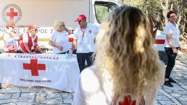 Red Cross staff hand out water bottles to tourists on the Acropolis site. (Bild: AFP or licensors)