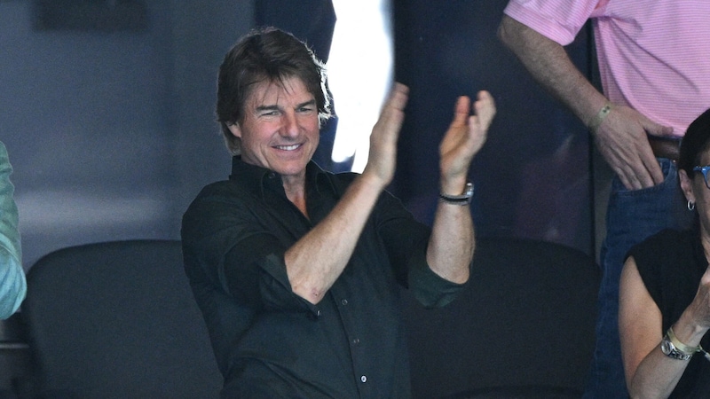 Tom Cruise claps his hands during a swimming competition at the 2024 Olympic Games - now he wants to make a splash himself. (Bild: APA Pool/Oli SCARFF / AFP)