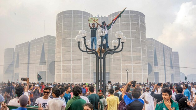 Demonstrators in Bangladesh's capital Dhaka celebrate the resignation and escape of head of government Sheikh Hasina. (Bild: AP)