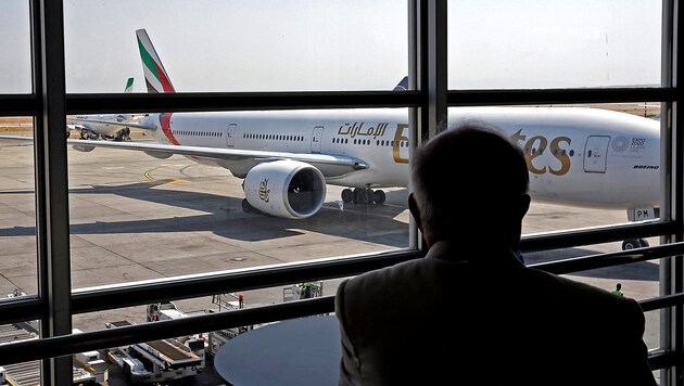 Ein Passagier beobachtet ein gelandetes Flugzeug der Emirates am Flughafen von Teheran. (Bild: APA/AFP)