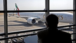 Ein Passagier beobachtet ein gelandetes Flugzeug der Emirates am Flughafen von Teheran. (Bild: APA/AFP)