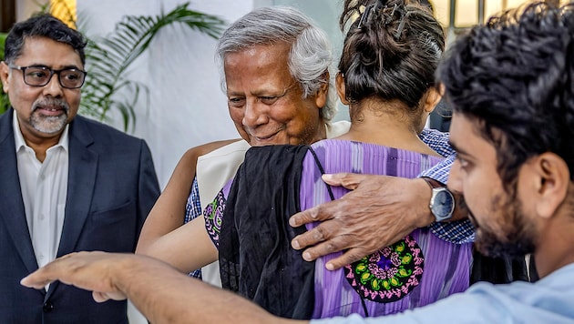 Mohammad Yunus wird von einer Anhängerin geherzt. (Bild: APA/AFP/Luis TATO)