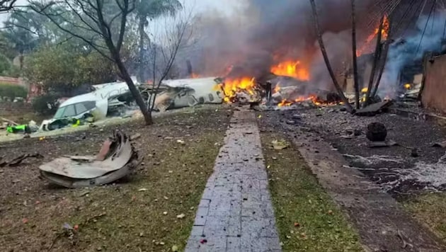 The burning wreckage of the plane lies in the middle of a road. (Bild: Screenshot G1)