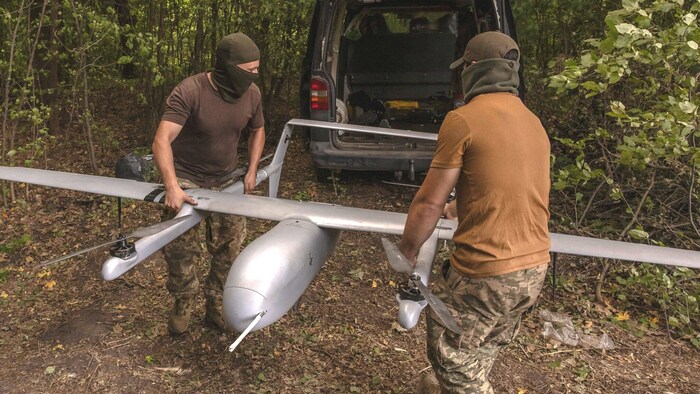 Ukrainian soldiers carrying a drone. 