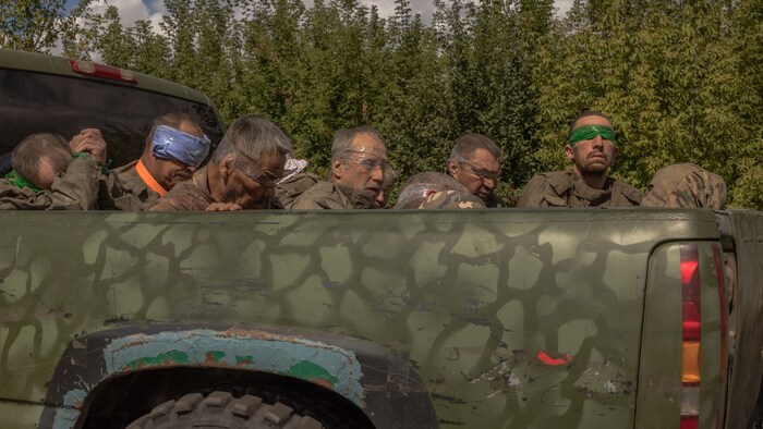 A Ukrainian military vehicle takes men in Russian uniform away from the Russian border.