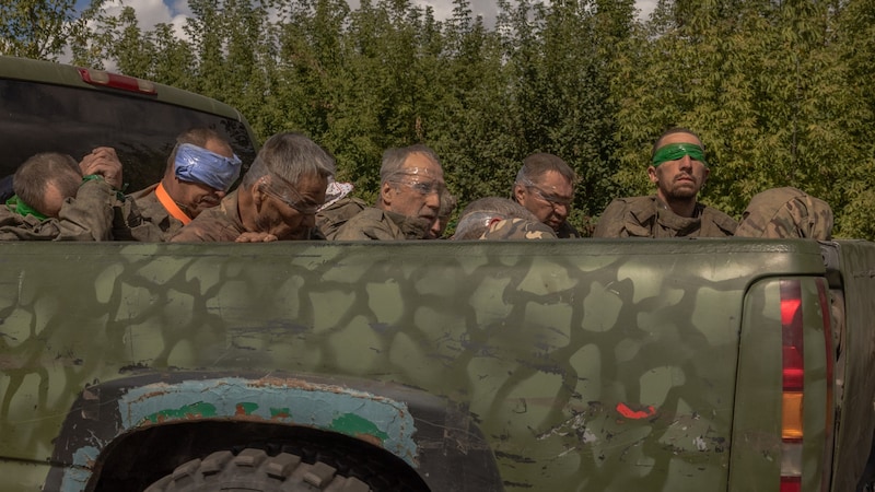 Ein ukrainisches Militärfahrzeug bringt Männer in russischer Uniform von der russischen Grenze weg. (Bild: APA/AFP/Roman PILIPEY)