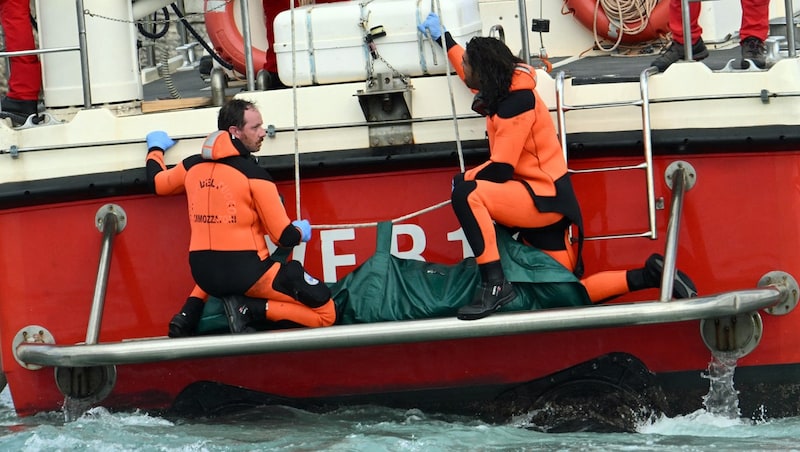 Taucher bringen einen Leichensack in den Hafen. (Bild: AFP/Alberto Pizzoli)