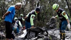 Einsatzkräfte mit dem Wrack eines abgestürzten Flugzeugs in Thailand (Bild: AFP/Sarot Meksophawannakul)