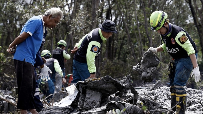 Einsatzkräfte mit dem Wrack des Flugzeugs (Bild: AFP/Sarot Meksophawannakul)