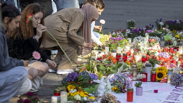 Eine Frau legt Blumen am Tatort nieder. (Bild: APA Pool/Thomas Banneyer)