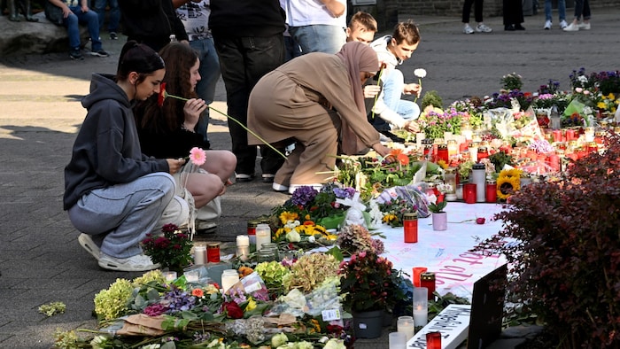Menschen legen Blumen zum Gedenken an die Opfer nieder.