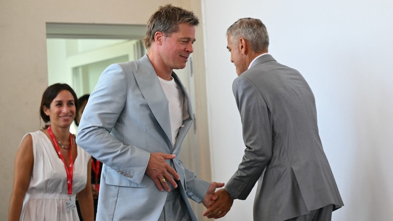 Brad Pitt (links) und George Clooney rührten in Venedig blödelnd die Trommel für den Action-Thriller „Wolfs“. (Bild: AFP)