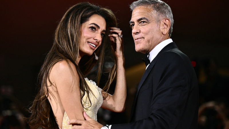 George Clooney wollte seine Amal am roten Teppich gar nicht mehr loslassen. (Bild: APA/AFP/Marco BERTORELLO)