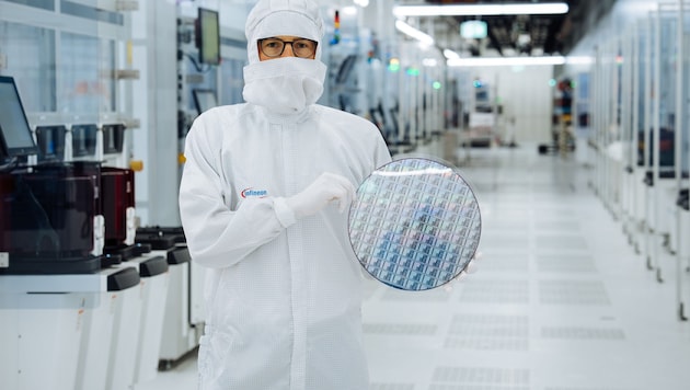 A technician in the clean room at Infineon Technologies in Villach holds a 300-millimeter gallium nitride wafer. (Bild: Infineon)