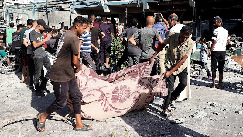 A victim of the airstrike wrapped in a carpet is taken away. (Bild: APA/AFP/Eyad BABA)