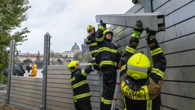 Firefighters set up a flood barrier near the Charles Bridge in the Czech capital Prague. (Bild: APA/AFP)