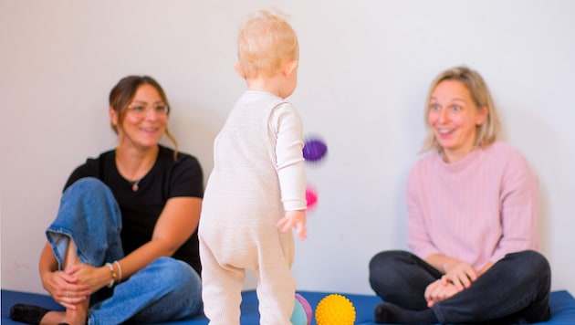 Montessori-Spielgruppe im EKIZ Linz; die kleine Emma ist fasziniert: Sie kann schon Bälle werfen, die Mama (re.) staunt. (Bild: Einöder Horst/Horst Einöder/Flashpictures)