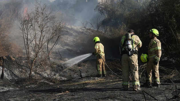 Feuerwehrleute bei Löscharbeiten nach dem Raketeneinschlag. (Bild: APA Pool/AFP/Menahem KAHANA)