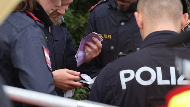 Police officers inspect the counterfeit money that washed ashore in Wels. (Bild: Matthias Lauber/laumat.at)