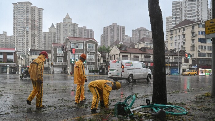 Workers are clearing debris from the streets in the wind and rain.