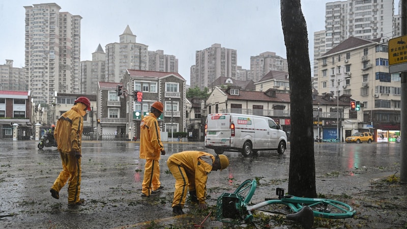 Arbeiter räumen bei Wind und Regen Trümmer von den Straßen. (Bild: APA/AFP/HECTOR RETAMAL)