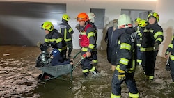 Mauerkirchener Feuerwehrleute transportieren Kinder in einer Scheibtruhe durch das Wasser (Bild: FF Mauerkirchen)