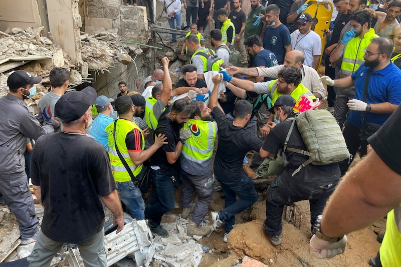 People carry a person out of the damaged building. (Bild: AP/Bilal Hussein)