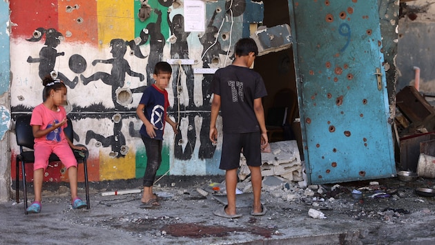 Displaced Israeli children take a picture of the damage to the former school building after the attack. (Bild: APA/AFP/Omar AL-QATTAA, Krone KREATIV)