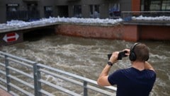 Ein Mann fotografiert in Breslau, Polen, ein Gebäude, das mit Sandsäcken gegen die Überschwemmungen geschützt ist. (Bild: APA/AFP/Sergei GAPON)