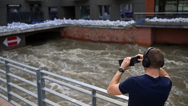 A man takes a photo of a building in Wroclaw, Poland, which is protected against the floods by sandbags. (Bild: APA/AFP/Sergei GAPON)