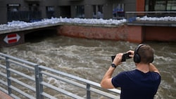 Ein Mann fotografiert in Breslau, Polen, ein Gebäude, das mit Sandsäcken gegen die Überschwemmungen geschützt ist. (Bild: APA/AFP/Sergei GAPON)