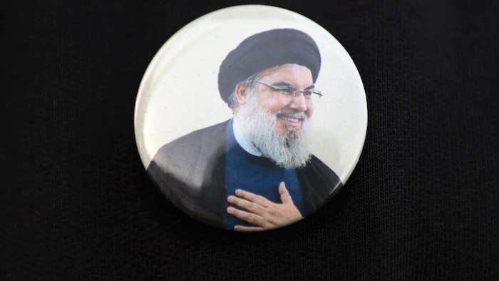 An Iraqi man wears a pin with Lebanese Hezbollah leader Hasan Nasrallah at the funeral of a ...