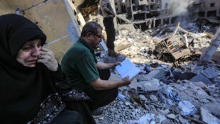 Nach den verheerenden Angriffen in Beirut: Eine Frau weint, während en Mann den Koran liest.