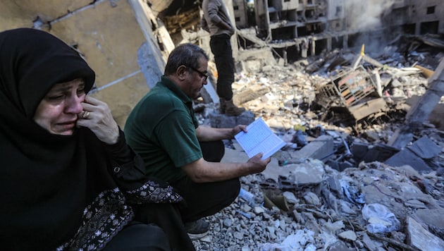 After the devastating attacks in Beirut: A woman cries while a man reads the Koran. (Bild: APA/AFP)