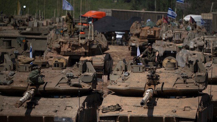 An Israeli soldier sits on the roof of a tank.