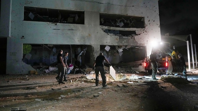 Israeli police officers work on a damaged school building that was hit by Iranian missiles in Gadera, Israel2. (Bild: AP)