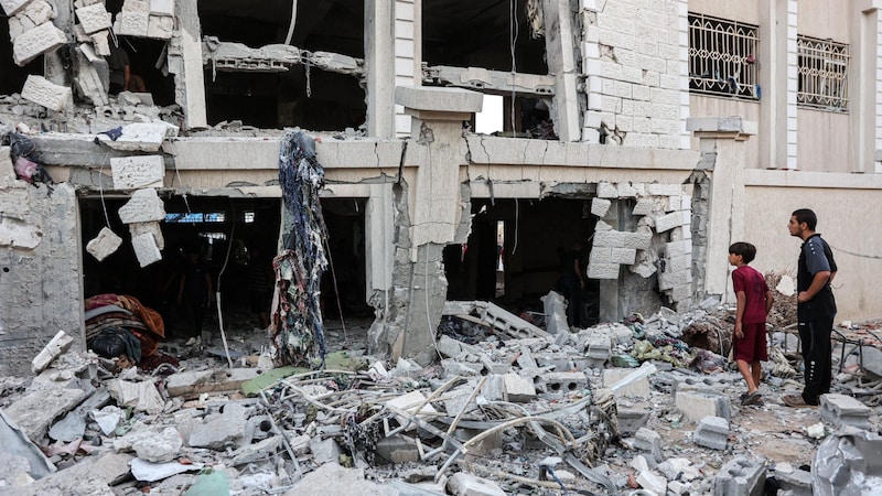 A man and a boy survey the damage after Israel attacked a school in the Gaza Strip. (Bild: APA/AFP)