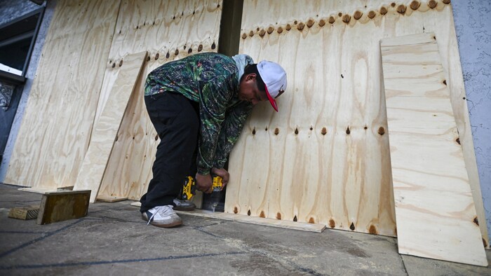 Dieser Mann vernagelt eilig noch die Hausfassade.
