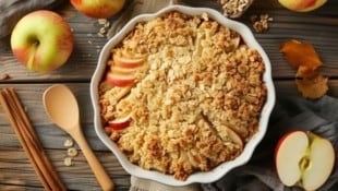 Besonders gut schmeckt dieser Crumble, wenn man ihn lauwarm und noch zusätzlich mit einer Kugel Vanilleeis serviert. (Bild: Paulius - stock.adobe.com)