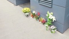 Vor dem Wohnhaus, in dem die 62-Jährige sterben musste, stehen nun zum Gedenken an sie Grabkerzen und Blumen. (Bild: Zwefo/Zwefo, Krone KREATIV)