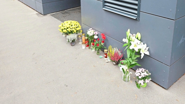 Vor dem Wohnhaus, in dem die 62-Jährige sterben musste, stehen nun zum Gedenken an sie Grabkerzen und Blumen. (Bild: Zwefo/Zwefo, Krone KREATIV)