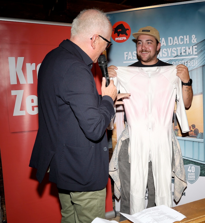 Presenter Andy Marek inspects Bontus' Olympic suit. (Bild: GEPA pictures)