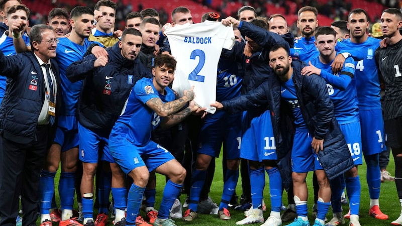 Das griechische Team feiert nach dem sensationellen Sieg mit einem Trikot von Baldock. (Bild: APA/PA Wire)