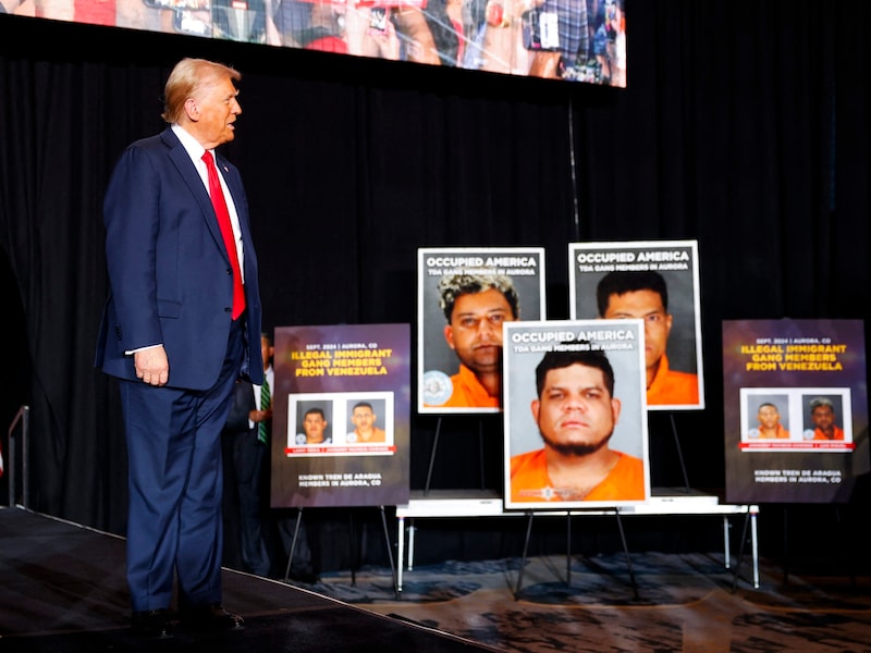 Trump in front of pictures of suspected gang members (Bild: APA Pool/Getty Images via AFP/GETTY IMAGES/Michael)