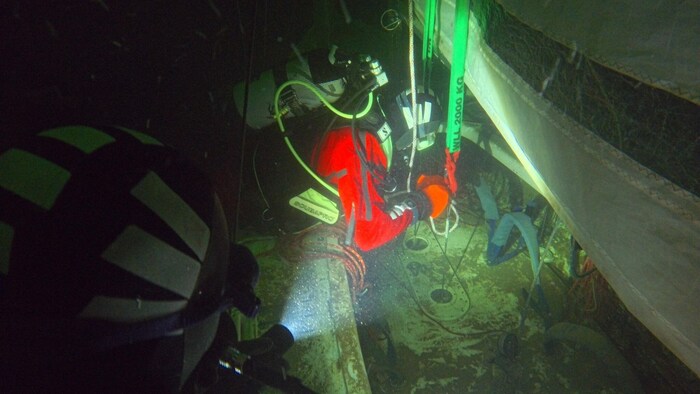 Taucher befestigten das Boot an der Hebevorrichtung.