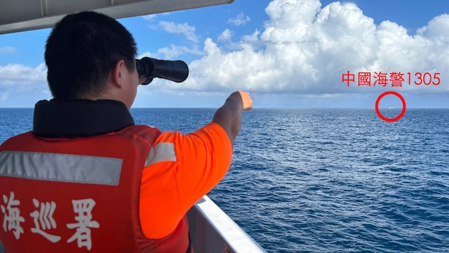 This photo released by the Taiwan Coast Guard on October 14, 2024 shows a Taiwan Coast Guard officer on a tanker off Pengjia Island (Keelung) while pointing at a Chinese Coast Guard vessel sailing in the distance outside Taiwan's territorial waters. (Bild: AFP)